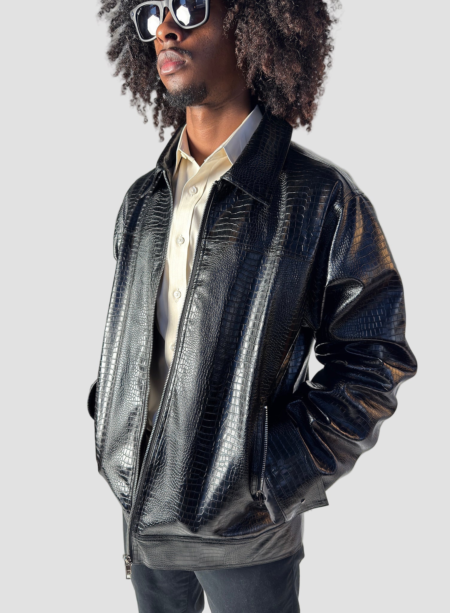 Person wearing a shiny black jacket and sunglasses indoors